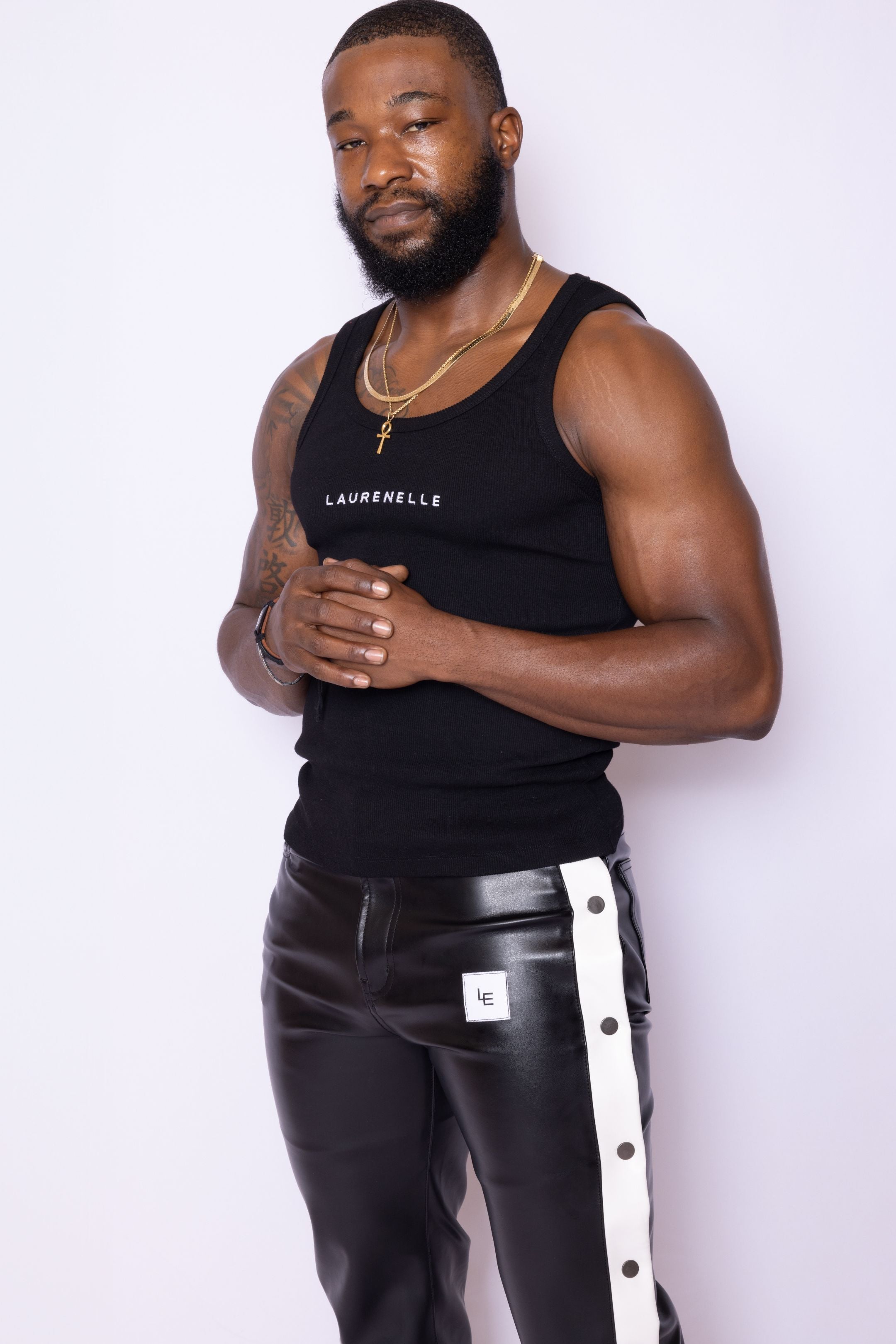 Cropped front view of Laurenelle men’s black vegan leather pants with side logo snap detail and white contrast trim.